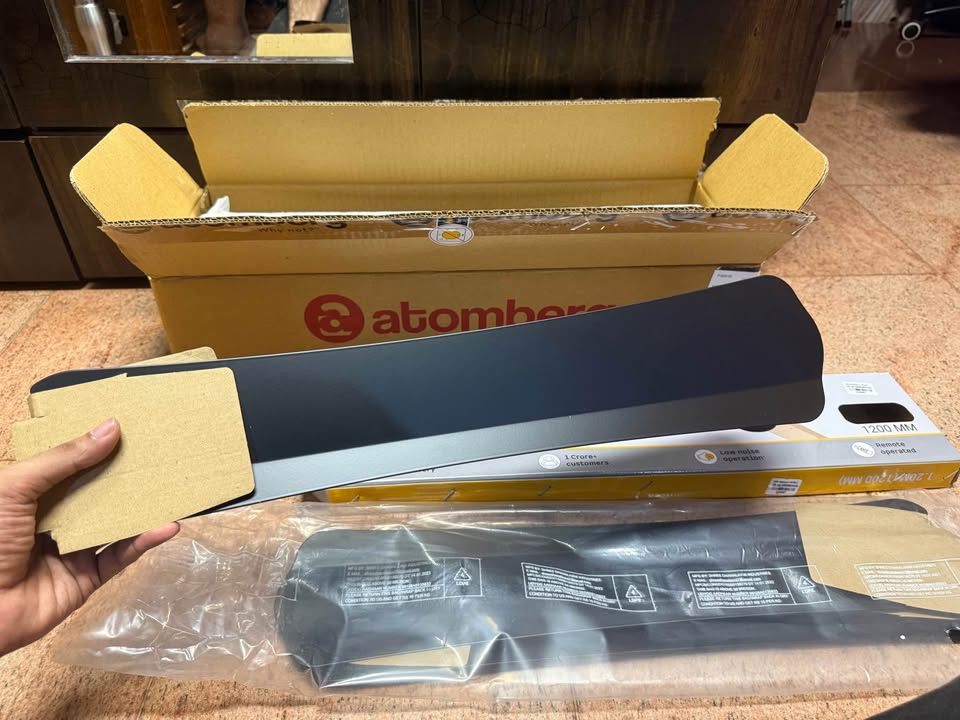 Close-up of Atomberg Renesa Halo Smart 1400mm BLDC ceiling fan blades during unboxing, showing the blade finish and design